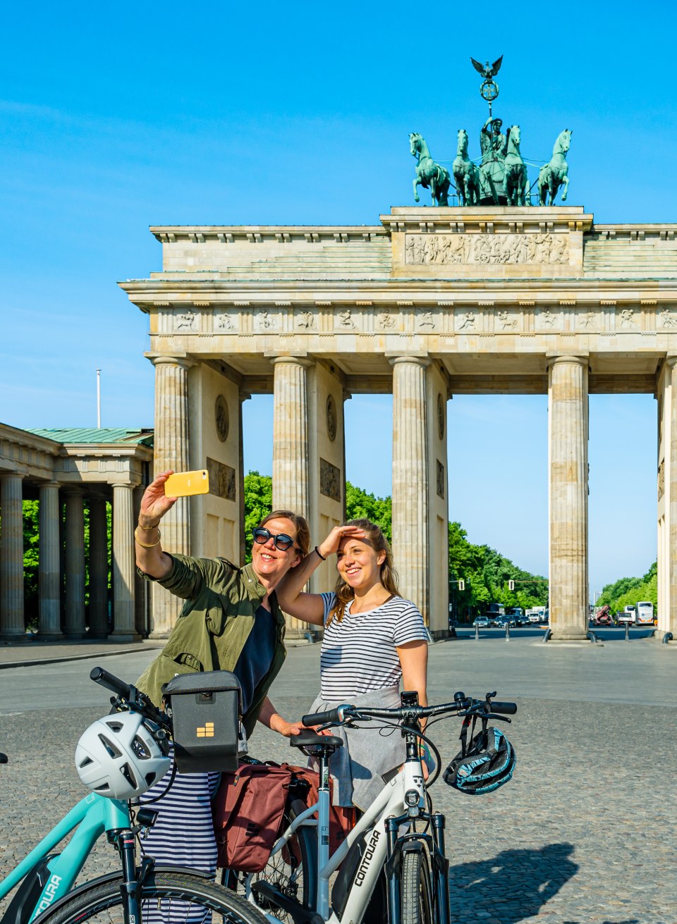 Aan de start: moeder en dochter bij de Brandenburger Tor in Berlijn, © TMV/Tiemann Moeder en dochter met fietsen nemen een selfie voor de Brandenburger Tor